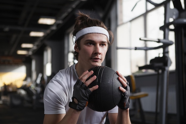 Foto atleta masculino enfocado con diadema haciendo ejercicio con balón medicinal