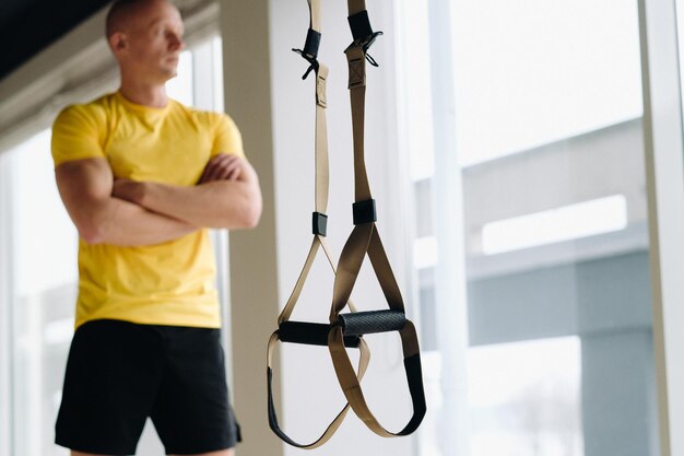 Un atleta masculino enfocado realizando un ejercicio en bucles funcionales en el gimnasio.