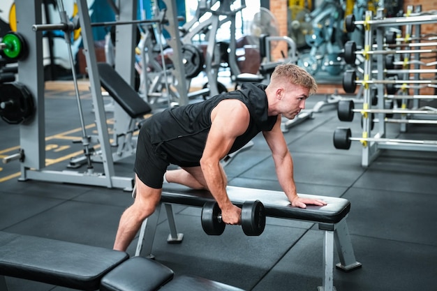 Atleta masculino exercitando na academia levantando pesos puxando articulações