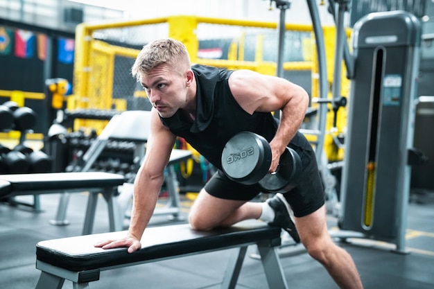 Atleta masculino exercitando na academia levantando pesos puxando articulações