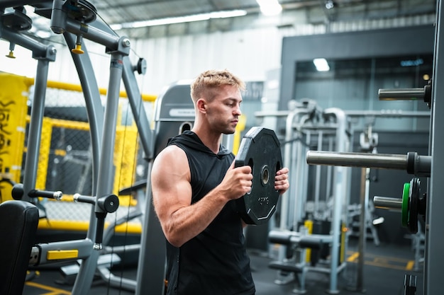 Atleta masculino exercitando na academia levantando pesos puxando articulações