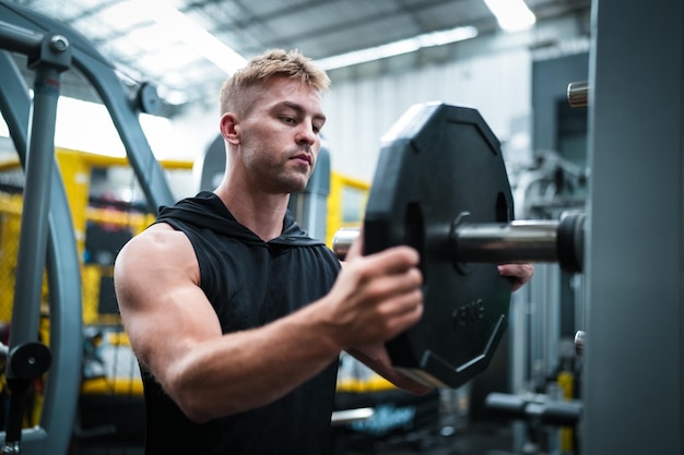 Atleta masculino exercitando na academia levantando pesos puxando articulações