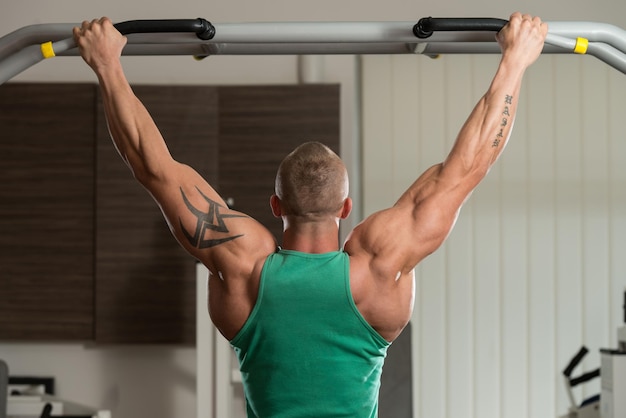 Atleta masculino fazendo pull ups ChinUps no ginásio