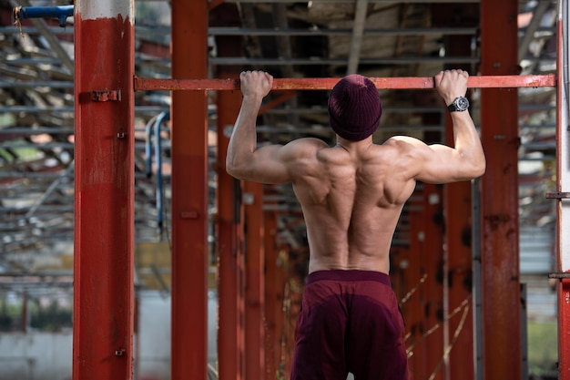 Atleta masculino fazendo pull ups no armazém