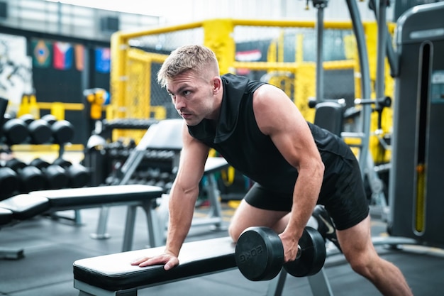 Atleta masculino haciendo ejercicio en el gimnasio levantando pesas tirando de las articulaciones