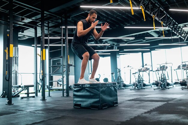 Atleta masculino negro motivado haciendo ejercicio de equilibrio en el cubo en el gimnasio moderno