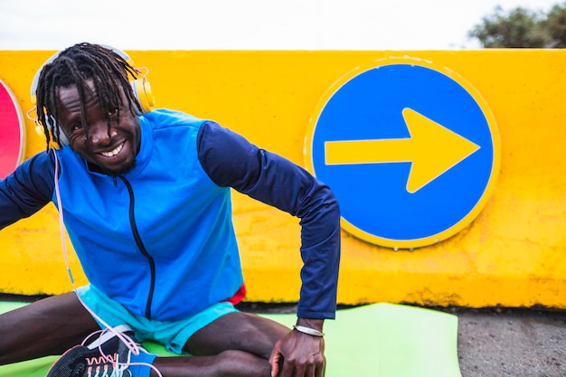 atleta masculino negro vestido com roupas esportivas, esticando-se antes de começar a se exercitar.