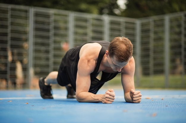 Atleta masculino pratica esportes abdominais e treina ao ar livre e fica na prancha