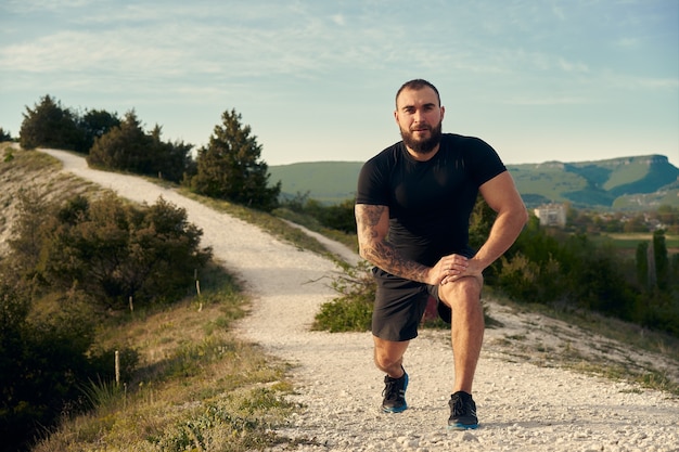 Atleta masculino se aquecendo antes de começar a correr nas montanhas