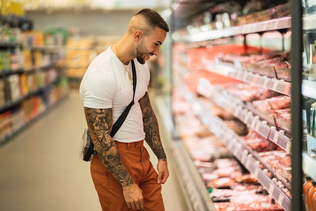 Atleta masculino tatuado caucasiano apto comprando comida na loja