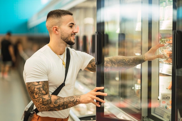 Atleta masculino tatuado caucasiano apto comprando comida na loja