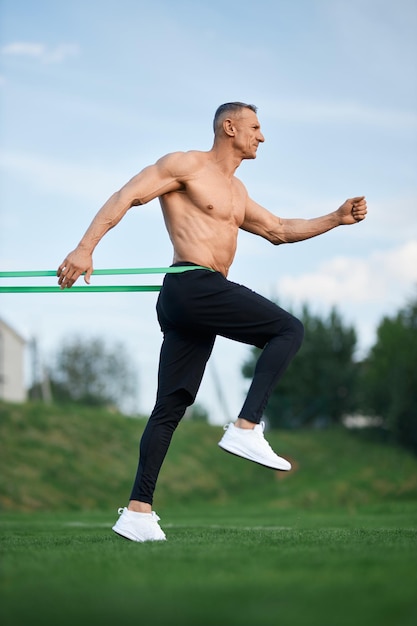 Atleta masculino usando banda de resistência para treino ao ar livre