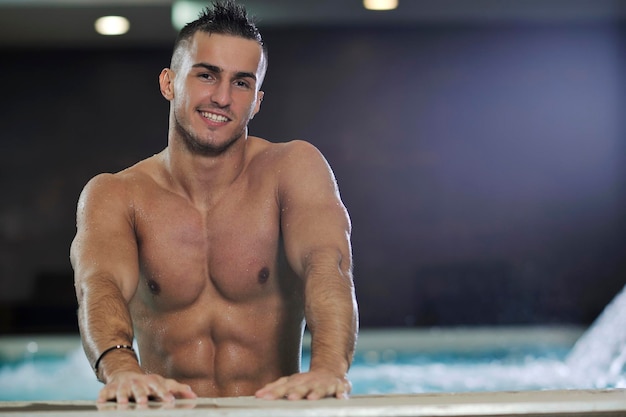 Atleta modelo jovem saudável e bonito homem macho na piscina interior do hotel