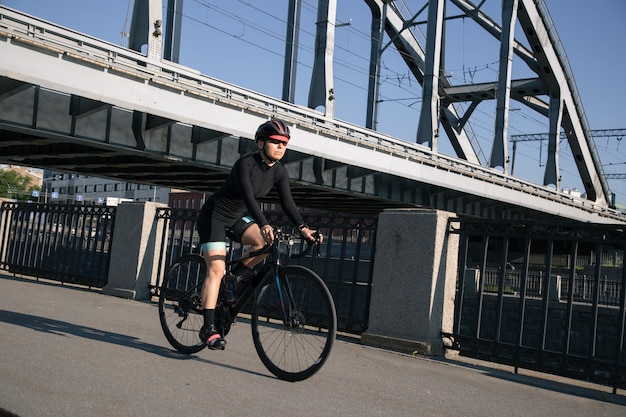 Atleta monta una bicicleta debajo de un puente ferroviario