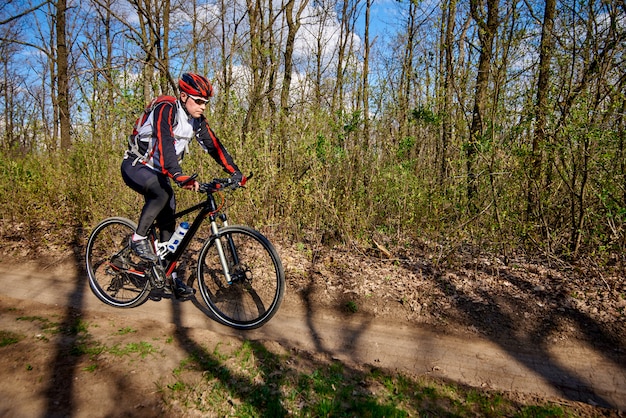 El atleta monta una bicicleta en la impasibilidad en el bosque.