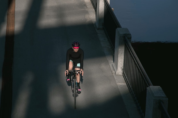 Atleta monta una bicicleta a lo largo del terraplén al amanecer.