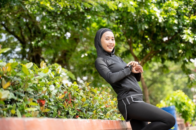 Atleta muçulmana relaxada exercitando seu corpo ao ar livre no parque