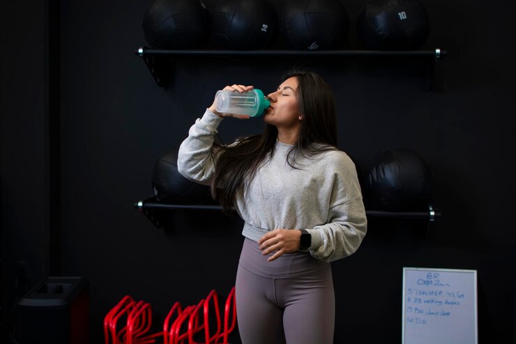 Atleta mulher tomando proteína de seu shaker antes de seu treino de ginástica