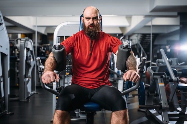 Atleta muscular en la máquina de ejercicio en el gimnasio