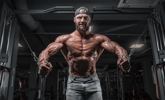 Atleta musculoso treinando em um crossover no ginásio. Bombeando o torso. Conceito de fitness e musculação.