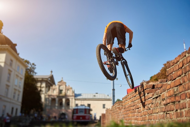 Atleta na cidade praticando salto em uma bicicleta de montanha