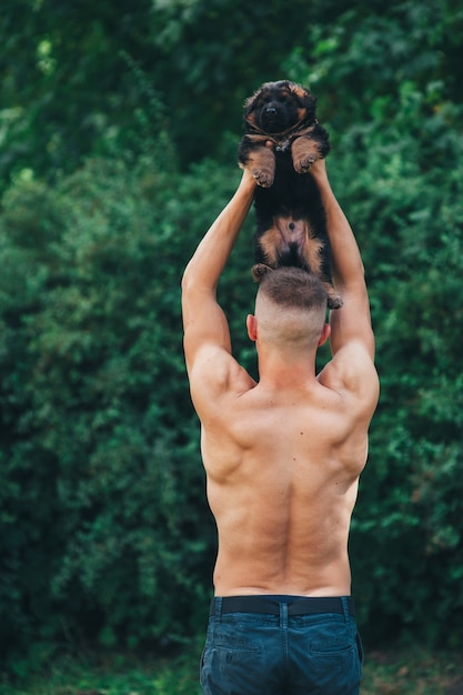 atleta niño sosteniendo en sus brazos, cachorro pastor alemán
