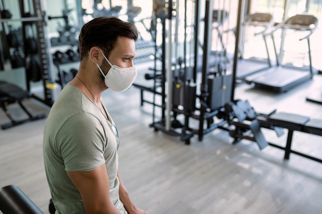 Atleta pensativo con mascarilla protectora en el club de salud