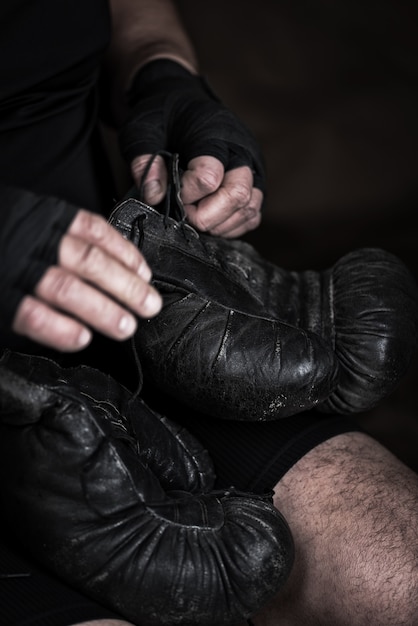 El atleta se pone guantes de boxeo de cuero negro.