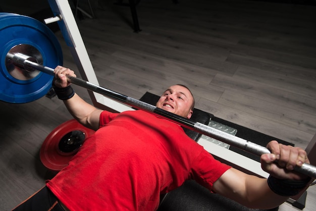 Atleta de Powerlifter intenta hacer press de banca con una barra pesada