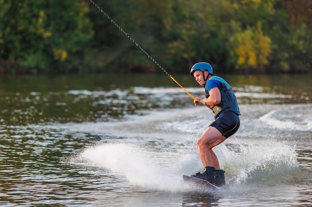 Un atleta realiza un truco en el parque acuático al atardecer. Jinete de Wakeboard