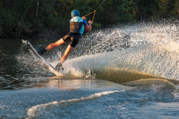 Un atleta salta sobre el agua Parque de Wakeboard al atardecer Un ciclista realiza un truco en la tabla