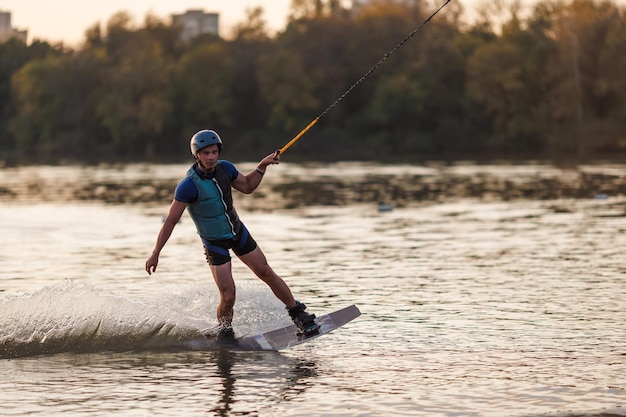 Un atleta salta sobre el agua Parque de Wakeboard al atardecer Un ciclista realiza un truco en la tabla