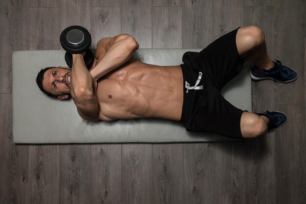 Foto atleta saludable ejercitando tríceps en el piso como parte del entrenamiento de culturismo