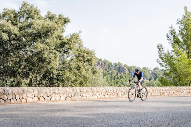 Atleta senior haciendo ciclismo de carretera en la imagen de las montañas con espacio de copia