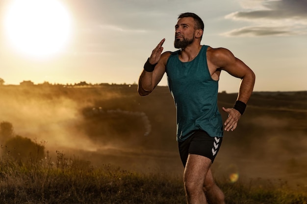 Atleta sprinter correr homem atlético forte correndo no fundo do pôr-do-sol vestindo roupas esportivas
