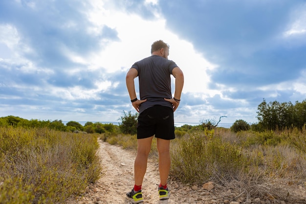 Foto atleta en su espalda de pie en un camino de tierra en el desierto