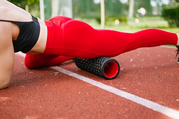 la atleta usa un rodillo de masaje para hacer ejercicio y eliminar el dolor, estirar y masajear los músculos