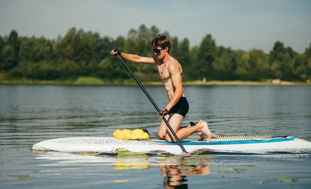 Atleta con un verano musculoso entrena en una tabla sup rema activamente