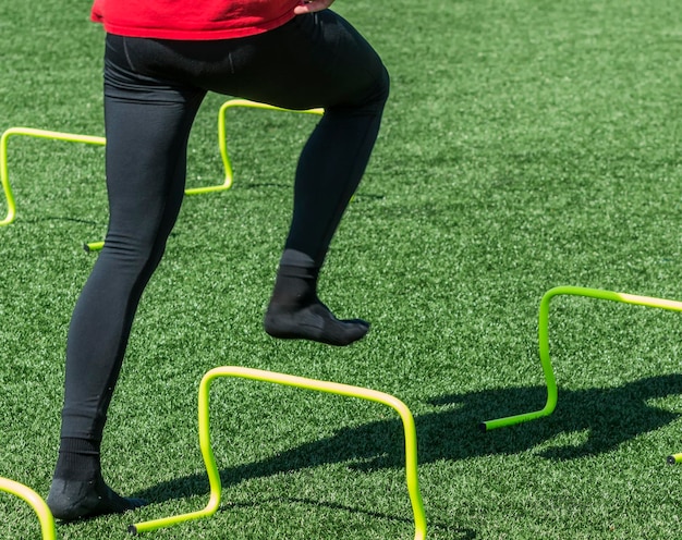 Un atleta vestido de spandex negro pisando mini obstáculos amarillos con calcetines