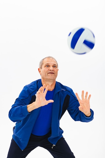 Atleta viejo canoso en chándal azul juega con pelota en blanco