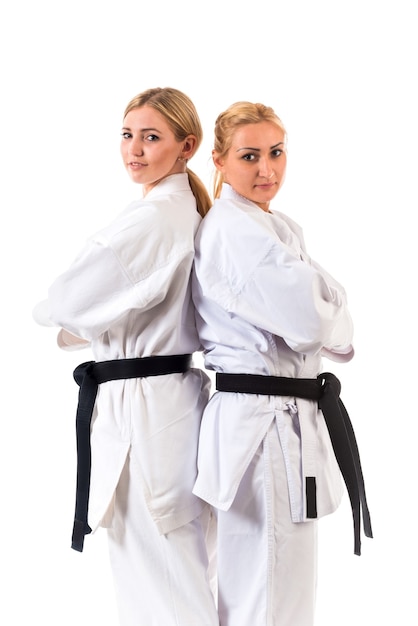 Foto atletas de duas garotas loiras usando quimono e faixas pretas posando em um carrinho de caratê
