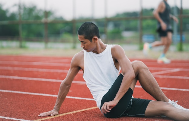 Atletas deportistas corredores con ropa deportiva blanca para estirar y calentar antes de practicar en una pista de atletismo en un estadio Concepto de deporte de corredor