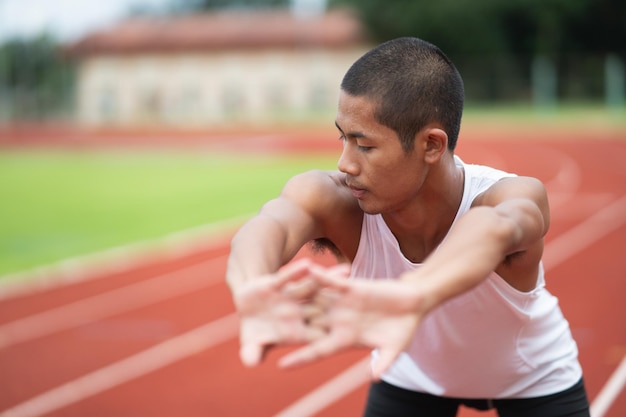 Atletas deportistas corredores con ropa deportiva blanca para estirar y calentar antes de practicar en una pista de atletismo en un estadio Concepto de deporte de corredor