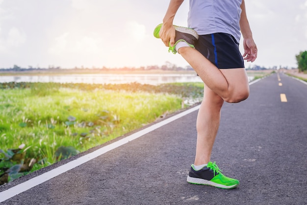 Atletas del hombre del corredor que prevengan para la práctica al aire libre en una pista del camino.