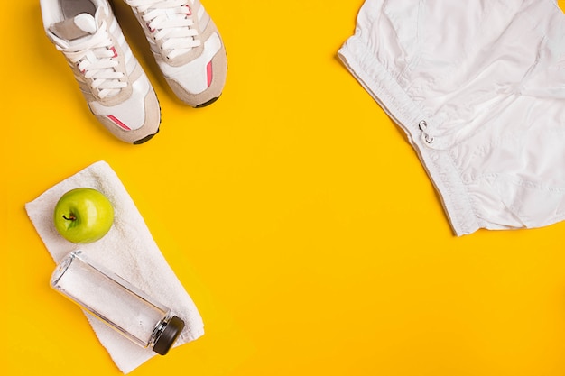 Los atletas con ropa femenina y botella de agua sobre fondo amarillo