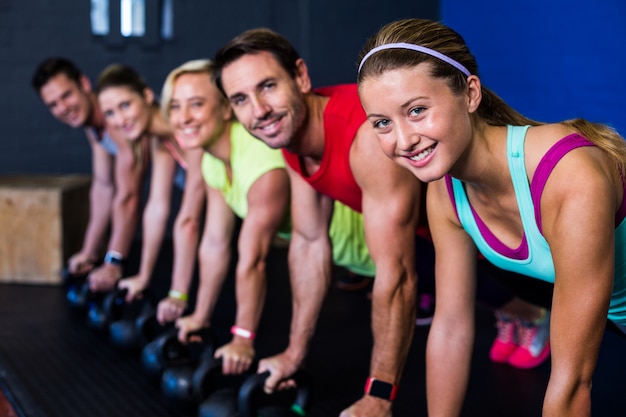 Atletas sorridentes exercitando com kettlebells