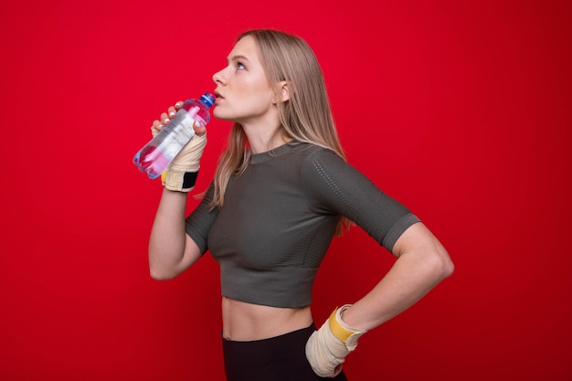 Atlética boxeadora bebe água na parede vermelha