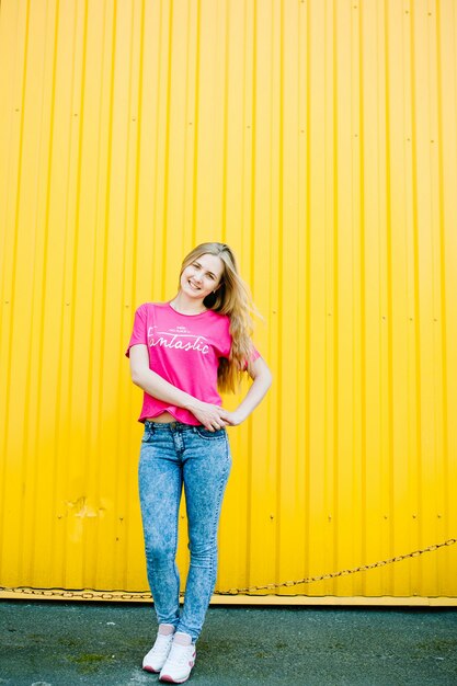 Atlética jovem bonita com longos cabelos loiros em uma camisa rosa e calça jeans azul.