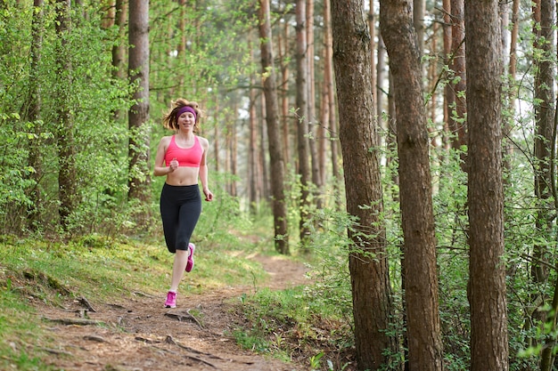 Atlética jovem de tênis rosa correr na floresta de primavera