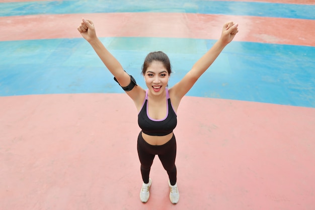 Atlética joven mujer asiática sana y belleza en ropa deportiva de pie y levantando las manos al aire libre para hacer ejercicio por la mañana. Chica activa ejercitarse en el ejercicio de estiramiento de bíceps. Concepto de deporte y estilo de vida